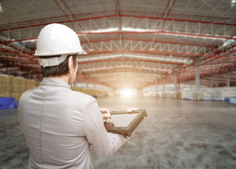Guide to a lighting assessment - worker with hardhat on assessing the light in a warehouse.