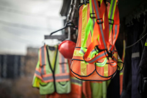What is the importance of PPE? - Worker protective equipment hanging on hooks outdoors.