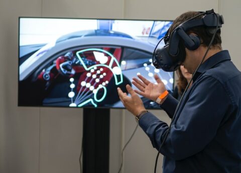 The use of virtual and augmented reality in safety training - Man wearing virtual reality headset looking at his hands with a screen in the background.