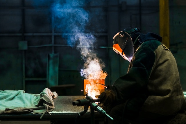 risks of welding fumes exposure - man welding with visible fumes coming from worksite