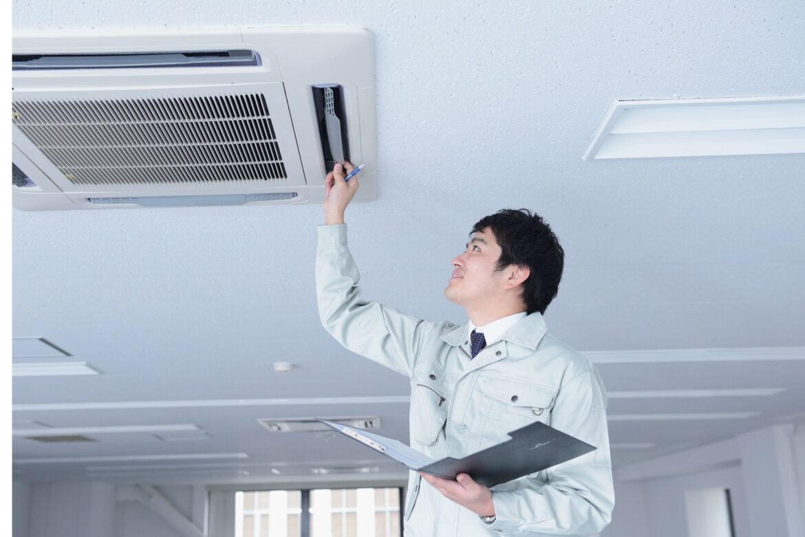 An inspector evaluates an air conditioning unit in an office, emphasizing the role of emissions testing companies in ensuring indoor air quality for healthier workplaces