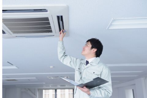 An inspector evaluates an air conditioning unit in an office, emphasizing the role of emissions testing companies in ensuring indoor air quality for healthier workplaces