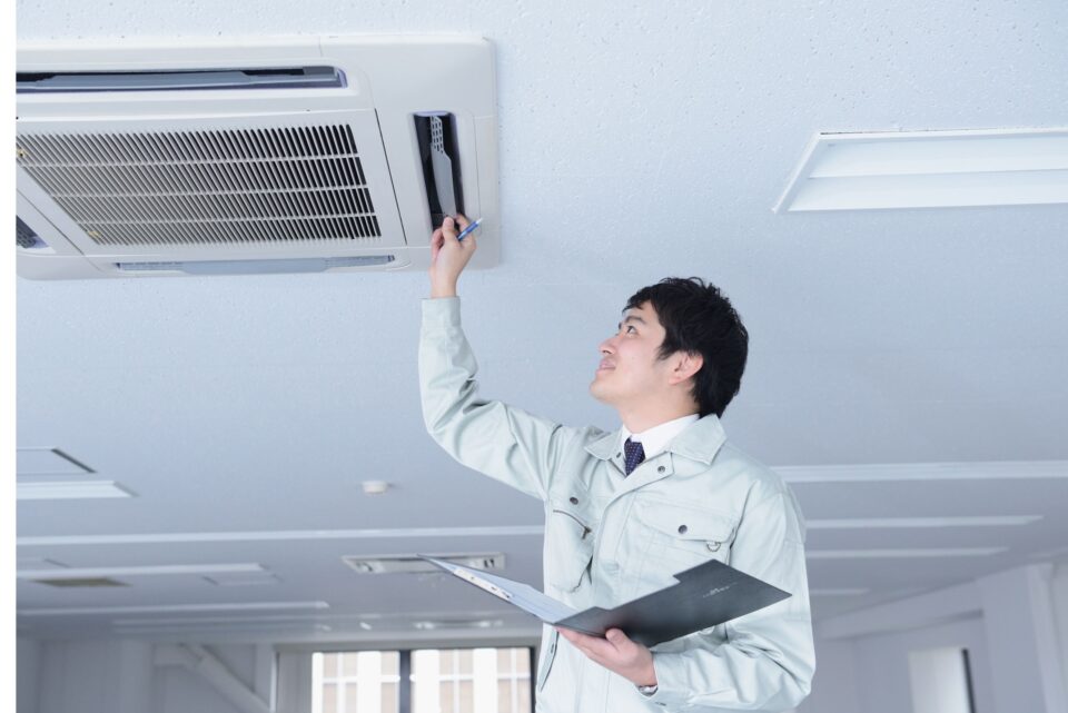 An inspector evaluates an air conditioning unit in an office, emphasizing the role of emissions testing companies in ensuring indoor air quality for healthier workplaces