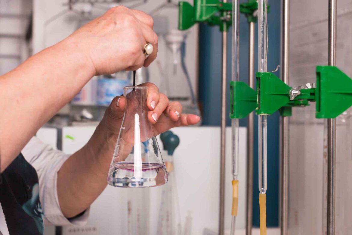 Laboratory technician conducting chemical testing with a conical flask at Apex Durban, ensuring workplace safety and compliance through accurate analysis.