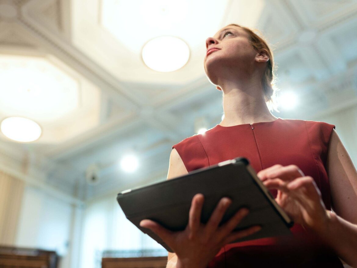 Professional assessing workplace lighting with a tablet, ensuring safe, compliant, and well-illuminated environments with Apex Environmental expertise