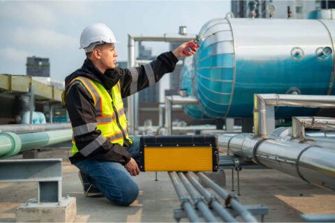 Engineer inspecting industrial piping system for leak detection and safety compliance under environmental regulations for the workplace.