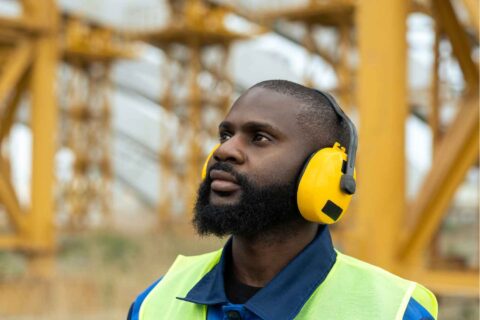 Worker wearing hearing protection during workplace noise monitoring in an industrial environment