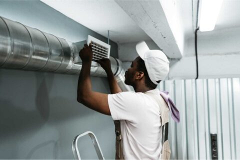 Technician installing workplace ventilation system in an industrial setting to improve airflow, air quality and employee health