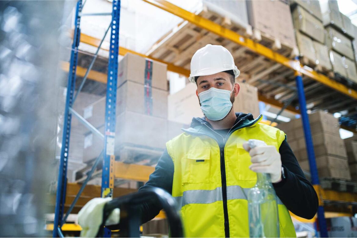 Occupational hygienist assessing workplace health risks in a warehouse environment using monitoring equipment to detect airborne exposures and hazards