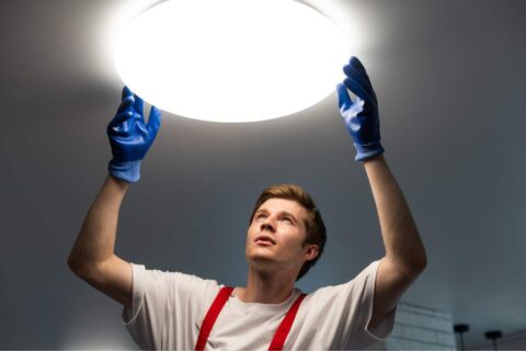Technician installing workplace lighting to improve safety and visibility in a commercial environment